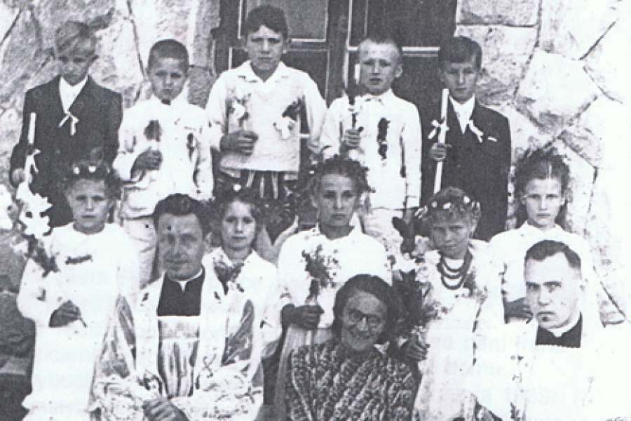 Historia - Pierwsza Komunia uczniów ze Stasikówki, siedzą od lewej: ks. Jan Krupiński, nauczycielka - Irena Radosz